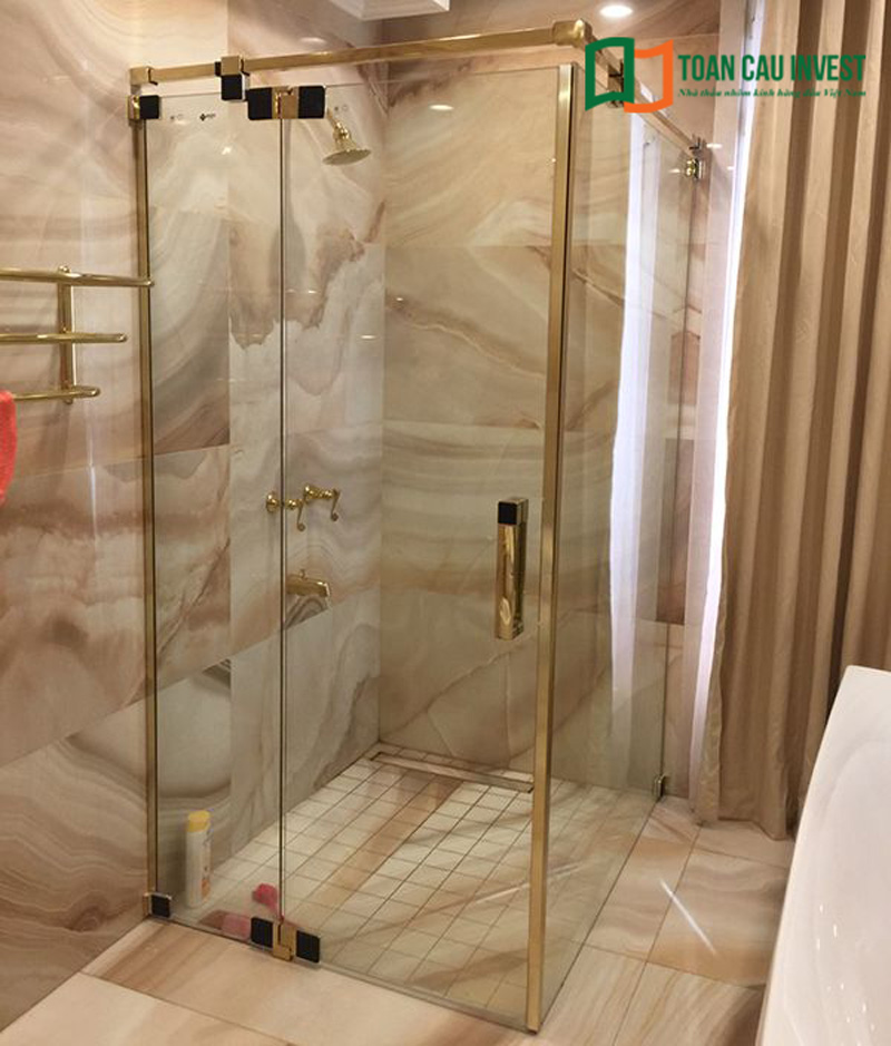 Vách kính tắm kết 90 độ với khung sơn mạ màu vàng nổi bật.