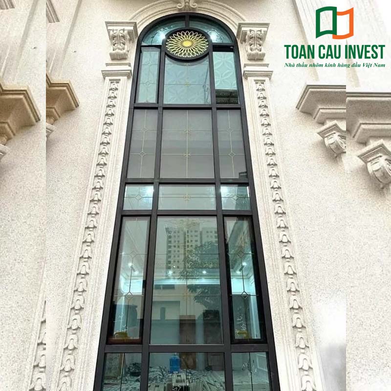 Cửa nhôm kính nan đồng cao cấp dạng vòm cao, kết hợp trang trí hoa văn tinh tế, phù hợp cho biệt thự cổ điển và công trình sang trọng