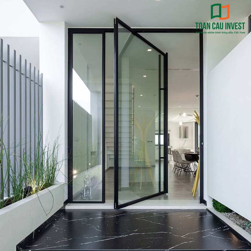 Cửa nhôm kính slim mở quay bản lề trục giữa, khung nhôm đen sang trọng, thiết kế tối giản cho lối vào hiện đại