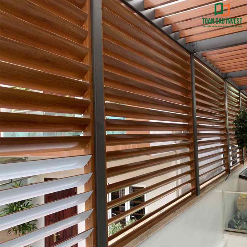 A close-up view of the operable sun-louver system in wood-grain finish, installed on the balcony and façade to provide effective shading while creating a distinctive architectural highlight.