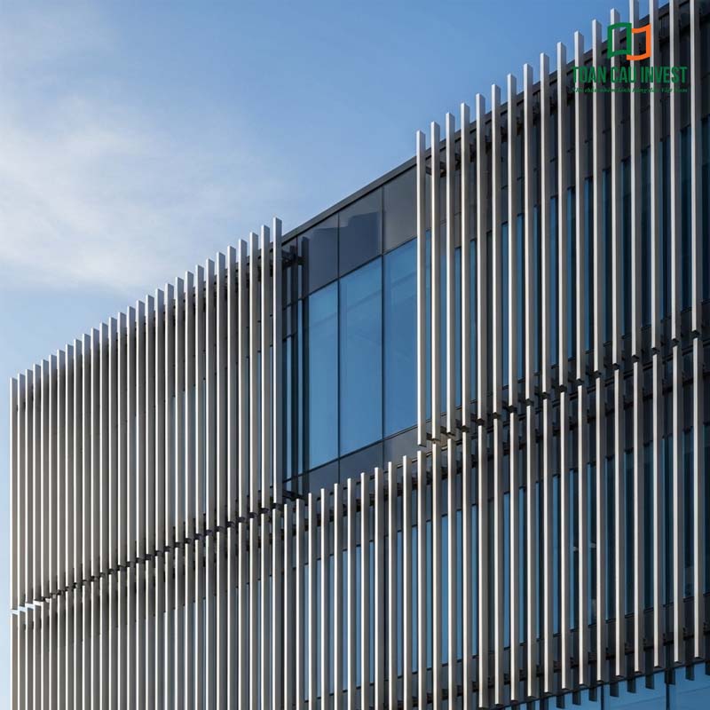 A modern building façade featuring gray aluminum Vertical Sun Louvers combined with tempered glass, creating a refined and sophisticated architectural focal point.