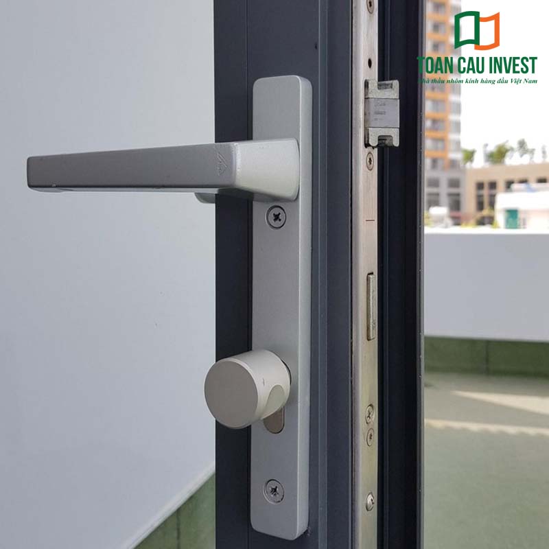 Khóa cửa nhôm kính màu bạc, tay nắm vuông, chốt xoay an toàn lắp đặt thực tế trên cửa nhôm Xingfa, độ bền cao và vận hành êm.