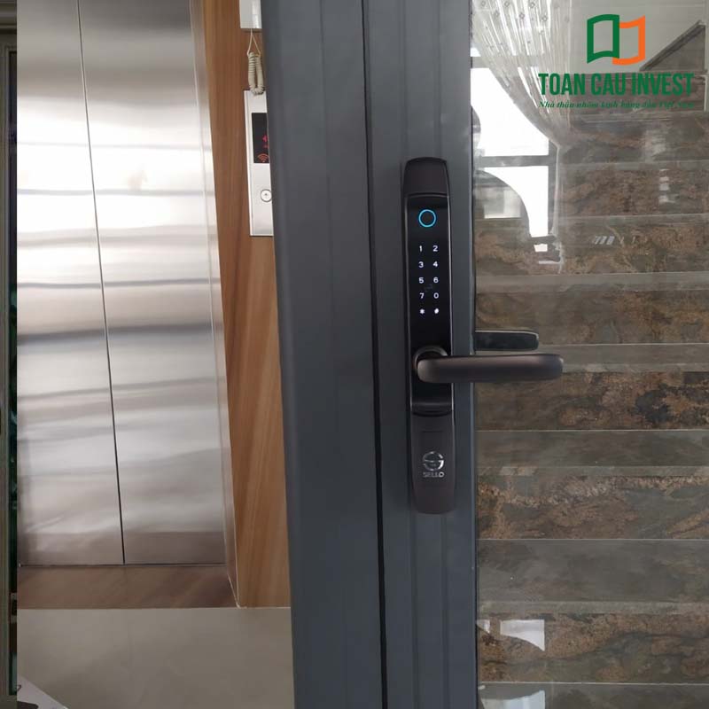 Khóa cửa nhôm kính thông minh lắp đặt thực tế tại nhà ở, hỗ trợ mở bằng mã số, vân tay và thẻ từ, tăng cường bảo mật cho cửa nhôm cao cấp.