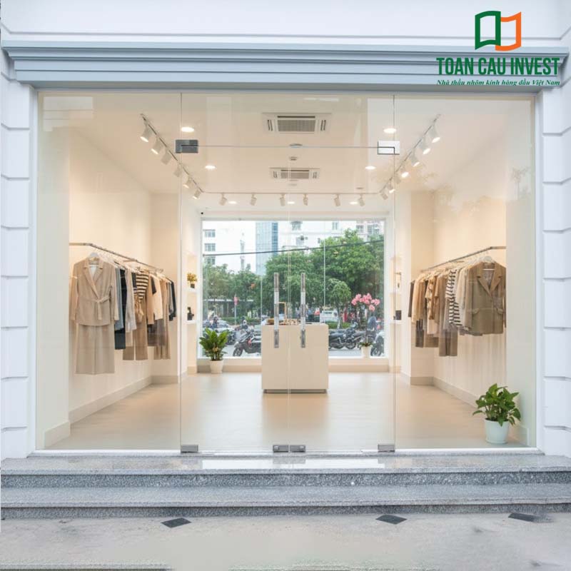 Cửa nhôm kính thủy lực trong suốt cho cửa hàng thời trang, thiết kế tinh tế giúp trưng bày sản phẩm nổi bật, tăng hiệu ứng không gian mở và hiện đại