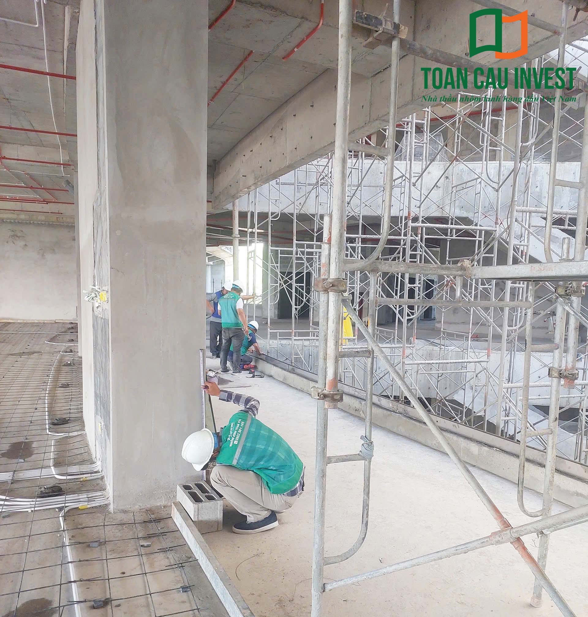 Hình ảnh nhôm kính thi công tại trung tâm đổi mới sáng tạo - đại học quốc gia Tp.HCM, công nhân đo đạc và kiểm tra vị trí lắp đặt khung nhôm tại khu vực ban công công trình.