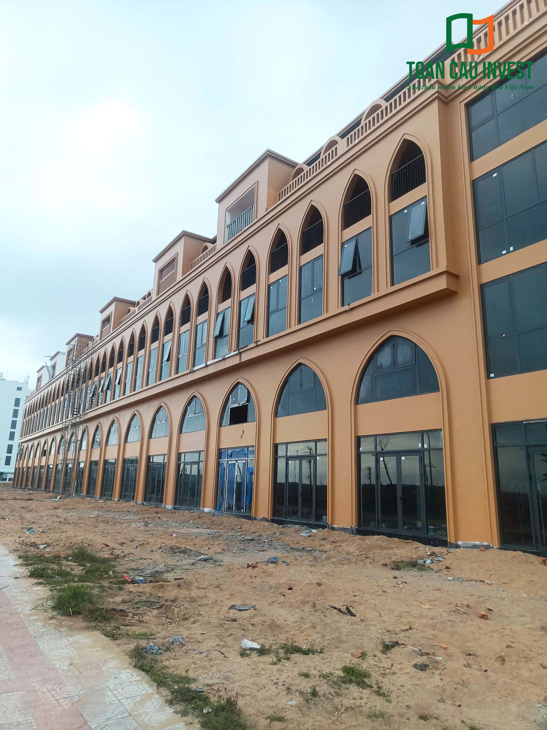 Tổng thể công trình shophouse với hệ cửa nhôm kính khổ lớn đang hoàn thiện mặt tiền bởi Toàn Cầu Invest.