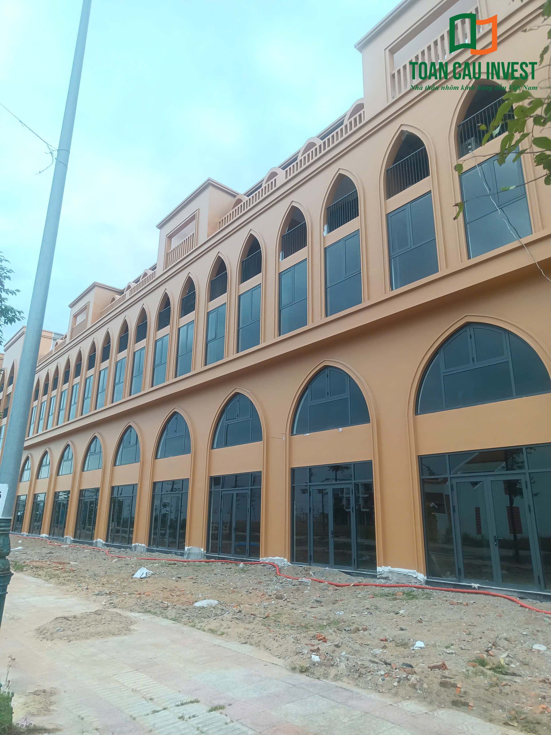 Mặt tiền dãy shophouse với hệ cửa nhôm kính khổ lớn và thiết kế vòm đặc trưng được thi công bởi Toàn Cầu Invest.