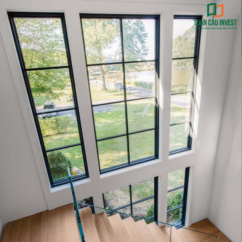 Vách kính lấy sáng cao tầng kết hợp cầu thang gỗ hiện đại, tận dụng tối đa ánh sáng tự nhiên, giúp không gian nội thất trở nên thoáng đãng và sang trọng.