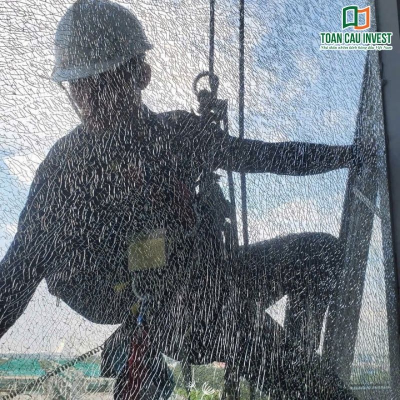 Hình ảnh kỹ thuật viên làm việc trên kính cường lực tự nổ, minh họa rủi ro trong thi công nếu không kiểm soát chất lượng kính.